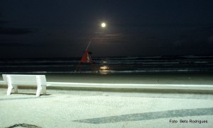 Beira-mar em Capão da Canoa, com a imagem da lua refletida na água 